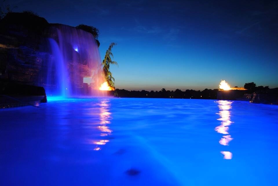 Cette image montre une grande piscine naturelle et arrière chalet sur mesure avec un point d'eau et du béton estampé.