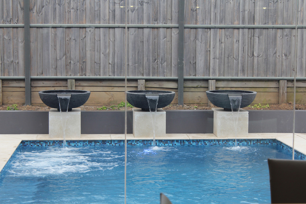 Foto di una piscina monocorsia design rettangolare di medie dimensioni e dietro casa con fontane e pavimentazioni in pietra naturale