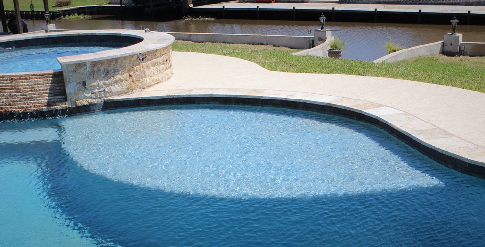 Esempio di una grande piscina naturale chic personalizzata dietro casa con una vasca idromassaggio e lastre di cemento