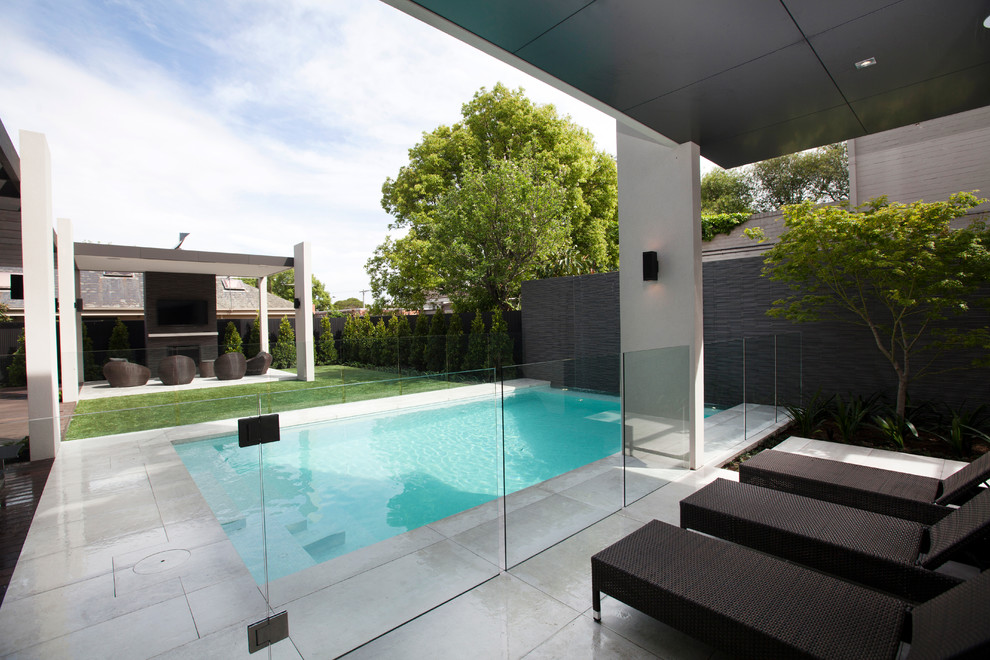 Esempio di una grande piscina minimalista rettangolare dietro casa con fontane