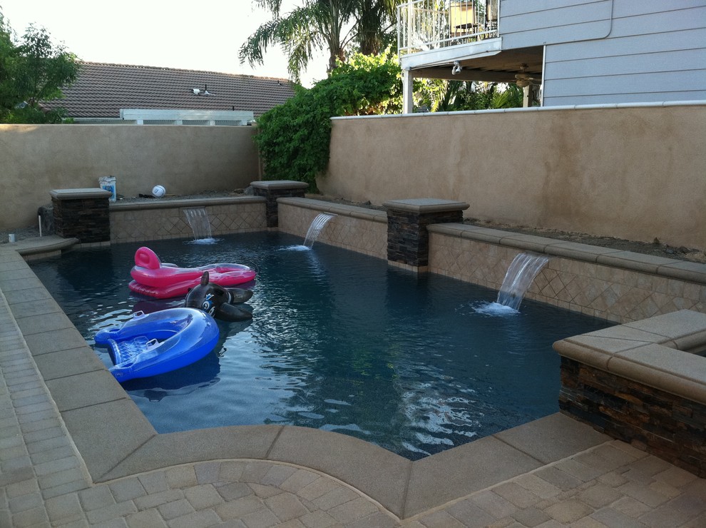 This is an example of a medium sized classic back rectangular lengths swimming pool in Orange County with natural stone paving.