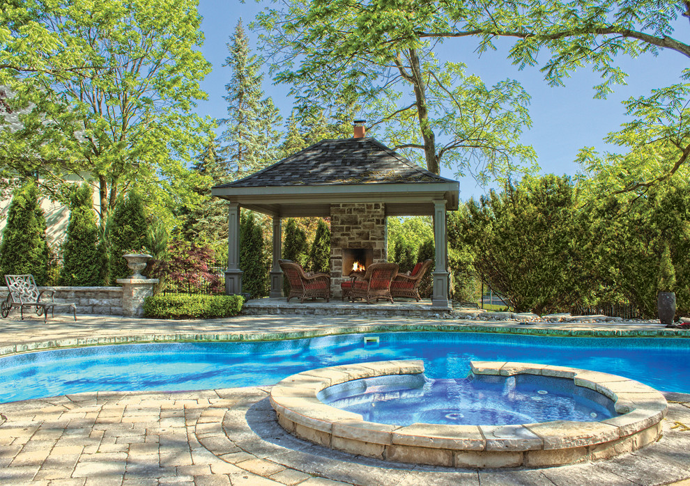 Large classic back kidney-shaped natural swimming pool in Toronto with brick paving and a pool house.