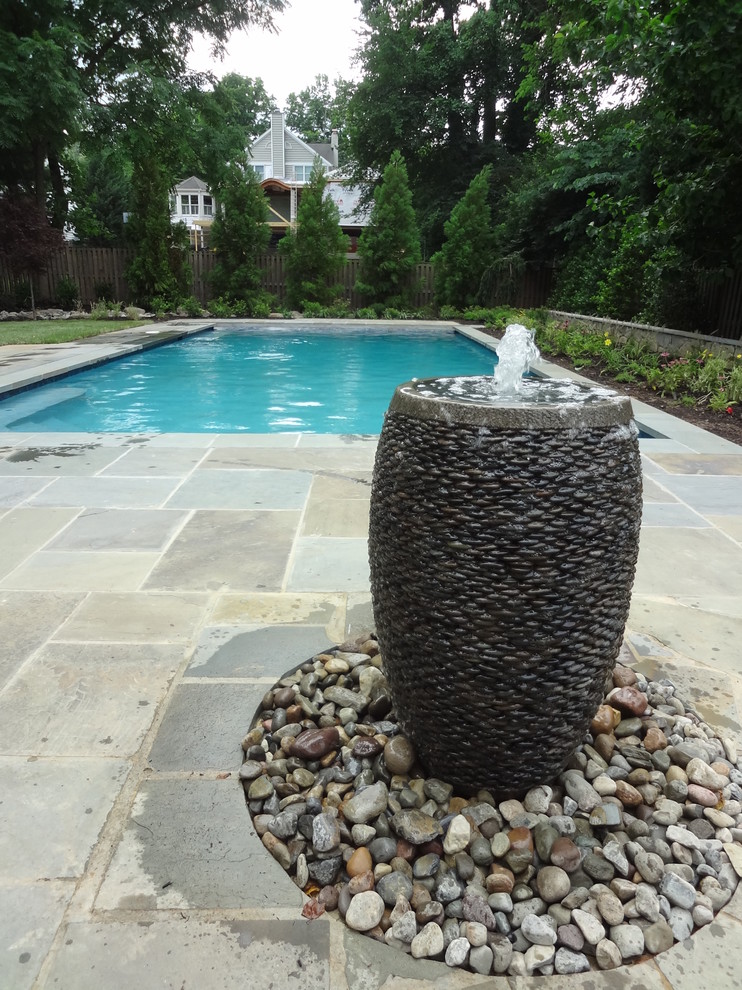 Diseño de piscina con fuente alargada actual grande rectangular en patio trasero con suelo de baldosas