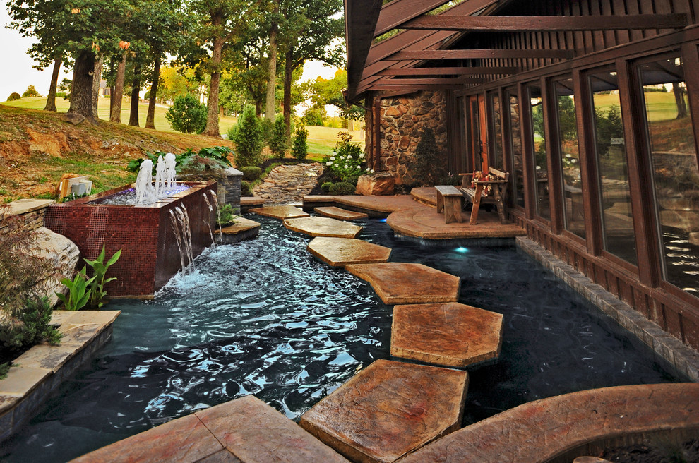 Diseño de piscina actual a medida en patio trasero con adoquines de piedra natural
