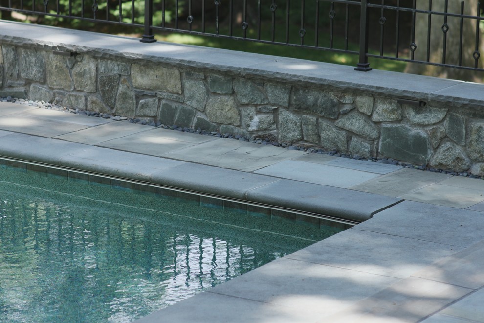 Modelo de piscina tradicional renovada pequeña rectangular en patio trasero con adoquines de piedra natural