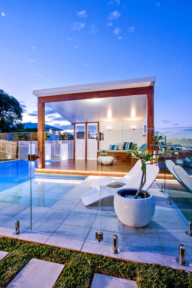 Imagen de casa de la piscina y piscina elevada minimalista de tamaño medio a medida en patio trasero con adoquines de piedra natural
