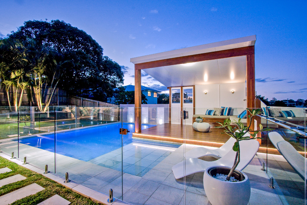 Modelo de casa de la piscina y piscina elevada moderna de tamaño medio a medida en patio trasero con adoquines de piedra natural