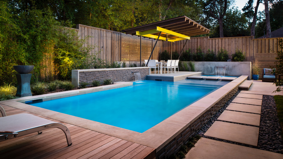 Photo of a medium sized modern back rectangular hot tub in Dallas with concrete slabs.
