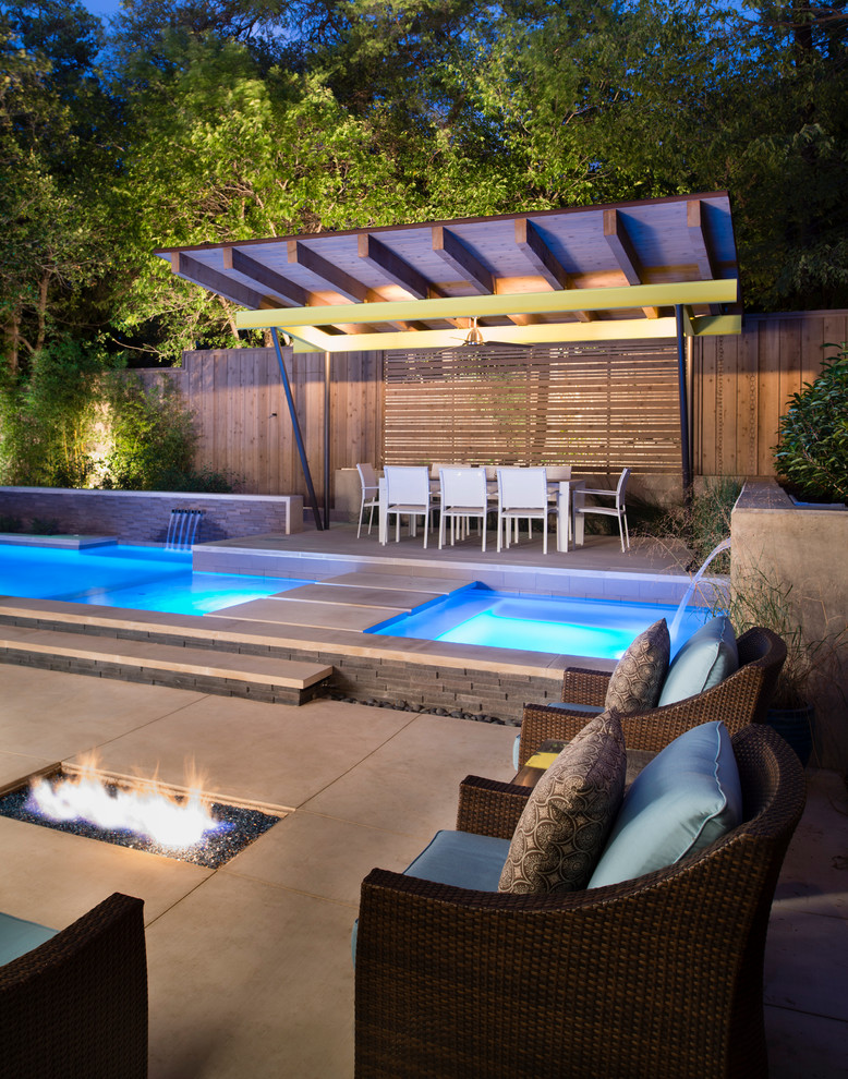 Idee per una piscina moderna rettangolare di medie dimensioni e dietro casa con una vasca idromassaggio e lastre di cemento
