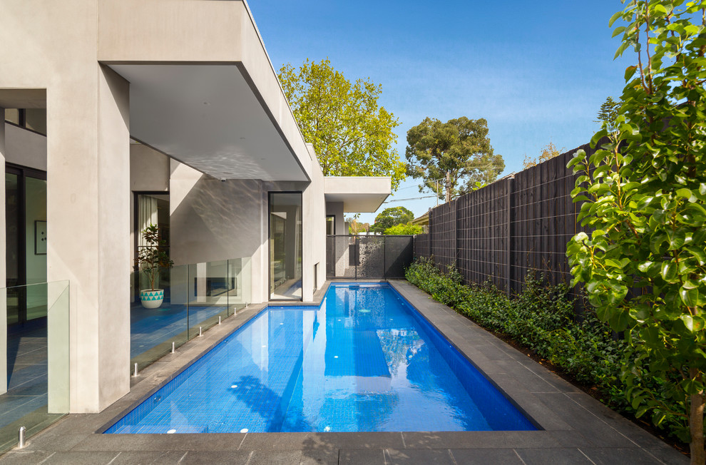 Inspiration for a contemporary l-shaped swimming pool in Melbourne with natural stone paving and fencing.