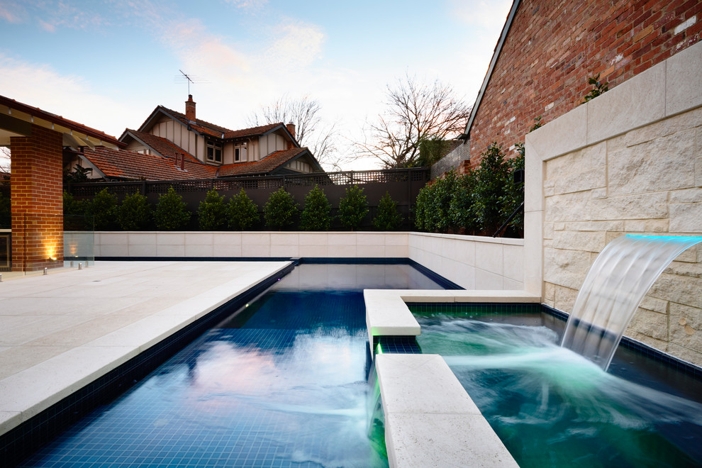 Contemporary swimming pool in Melbourne with a water feature.