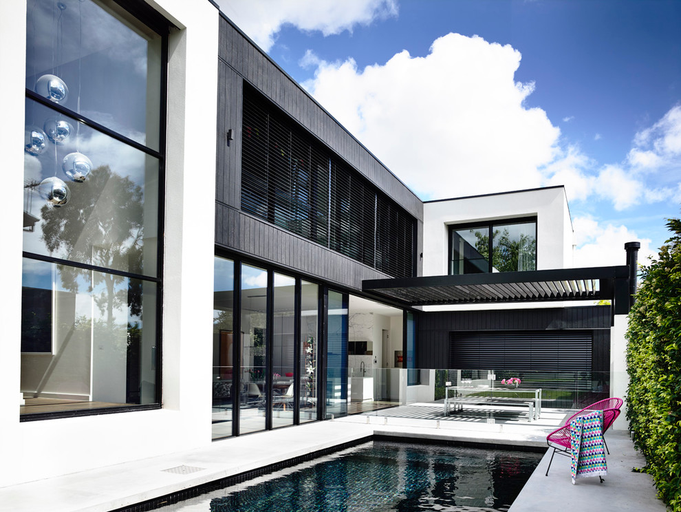 Esempio di una piscina monocorsia moderna rettangolare dietro casa con una vasca idromassaggio e lastre di cemento