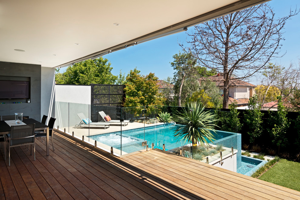 Ejemplo de piscina infinita actual grande rectangular en patio trasero con adoquines de hormigón