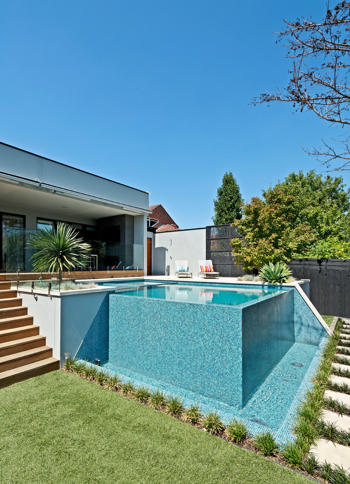 Foto de piscina infinita minimalista grande rectangular en patio trasero con adoquines de hormigón