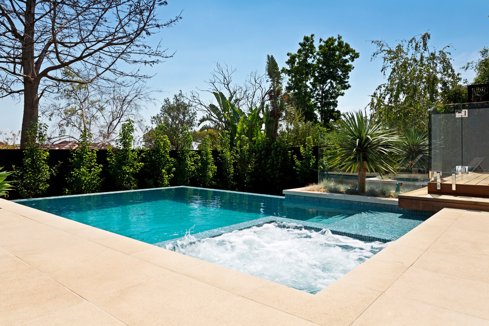 Свежая идея для дизайна: большой прямоугольный бассейн-инфинити на заднем дворе в современном стиле с мощением тротуарной плиткой - отличное фото интерьера