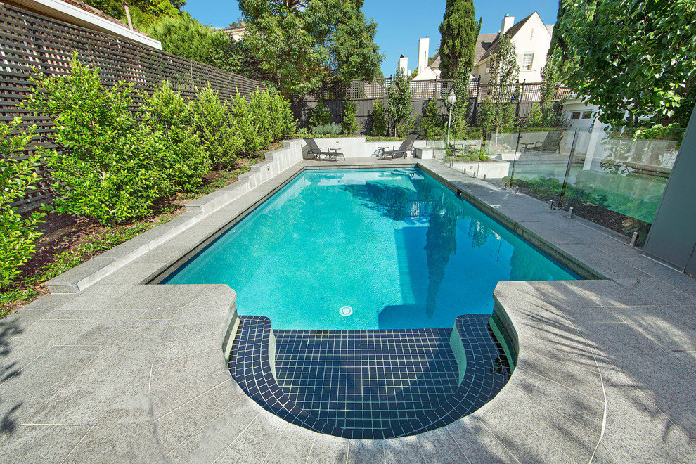 Ispirazione per una piscina naturale vittoriana rettangolare di medie dimensioni e dietro casa con pavimentazioni in pietra naturale