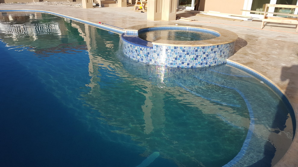 Ejemplo de piscinas y jacuzzis clásicos grandes a medida en patio trasero con adoquines de piedra natural