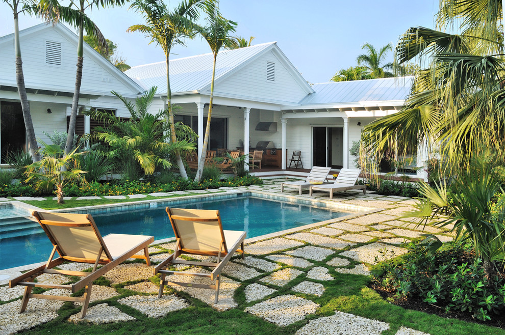 Ejemplo de piscina tropical, rectangular, con adoquines de piedra natural