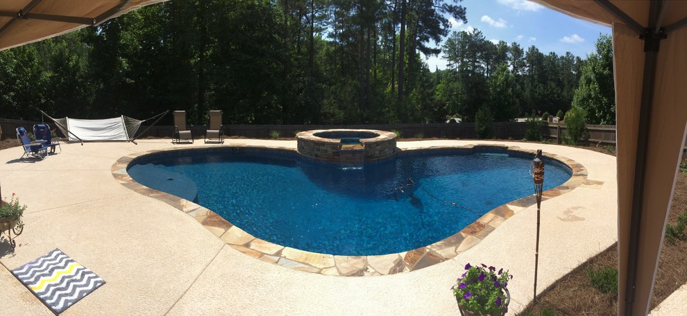 Foto på en mellanstor amerikansk pool på baksidan av huset, med spabad och naturstensplattor