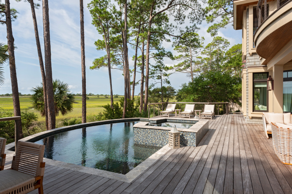 Aménagement d'une piscine bord de mer sur mesure avec un bain bouillonnant et une terrasse en bois.