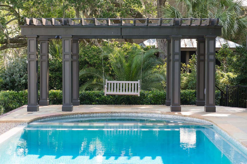 Imagen de piscina infinita clásica renovada grande redondeada en patio trasero con adoquines de piedra natural