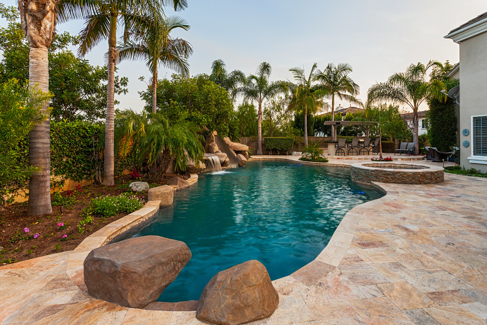 Inspiration for a world-inspired back custom shaped swimming pool in San Diego with a water feature and natural stone paving.