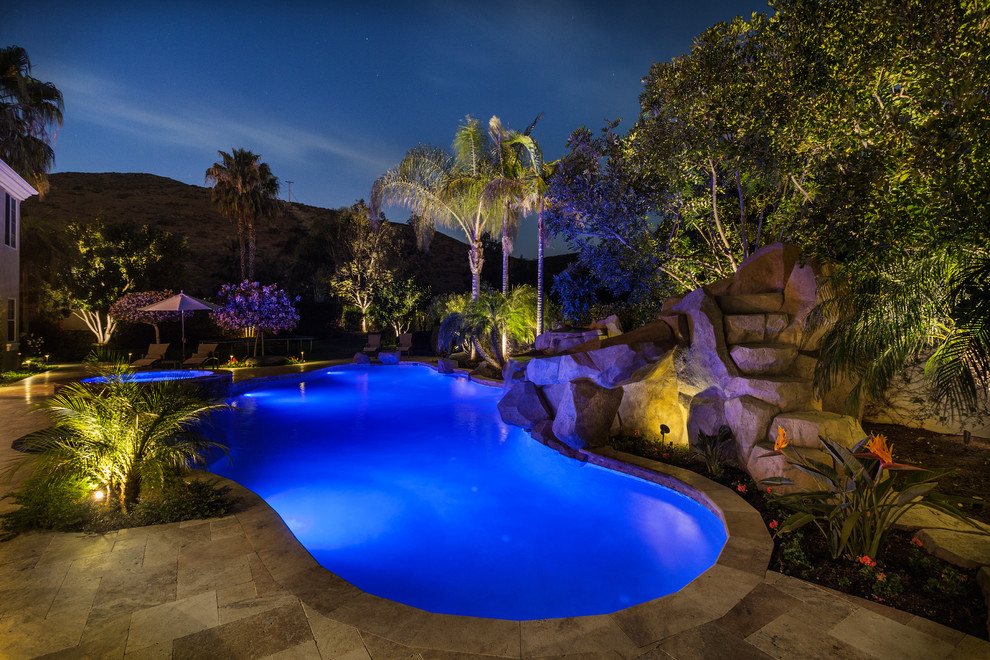 Foto de piscina con fuente exótica a medida en patio trasero con adoquines de piedra natural