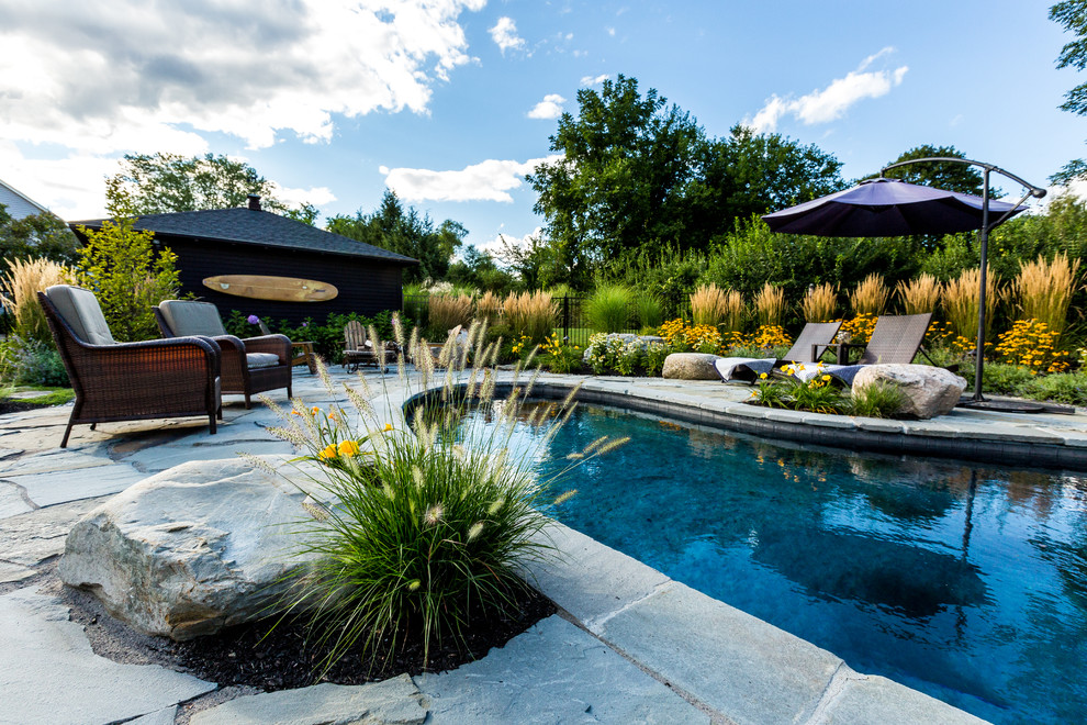 Diseño de piscina natural rural de tamaño medio tipo riñón en patio trasero con adoquines de piedra natural