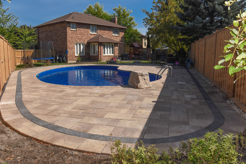 Imagen de piscina actual grande tipo riñón en patio trasero con adoquines de hormigón