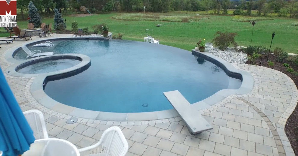 Esempio di una piscina a sfioro infinito design a "C" di medie dimensioni e dietro casa con una vasca idromassaggio