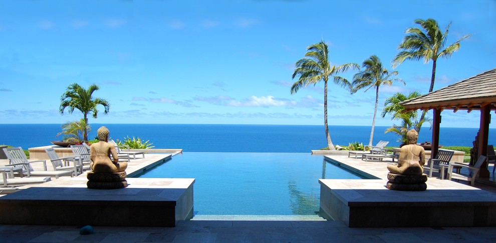 Example of a large island style backyard concrete and rectangular infinity pool design in Hawaii