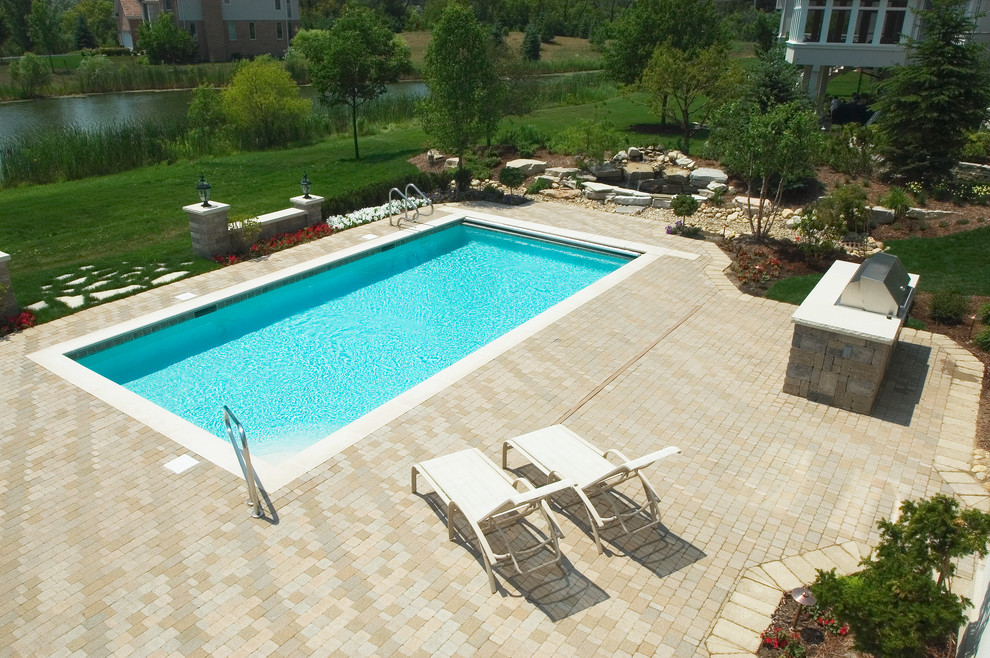 Foto de piscina alargada tradicional pequeña rectangular en patio trasero con adoquines de hormigón