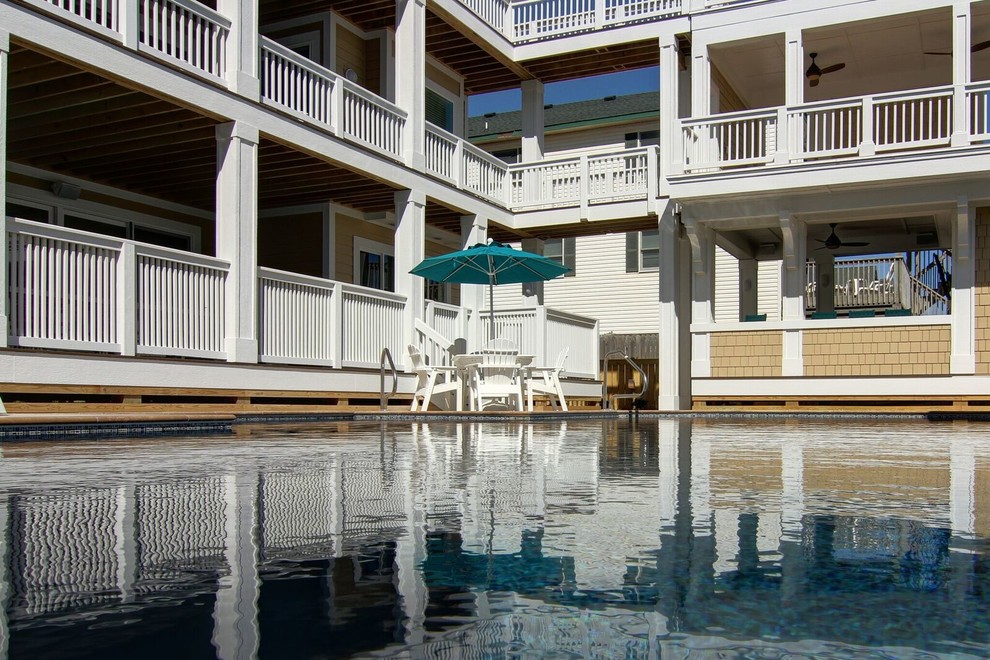 Immagine di una piscina monocorsia stile marinaro rettangolare di medie dimensioni e dietro casa con una vasca idromassaggio e pavimentazioni in cemento