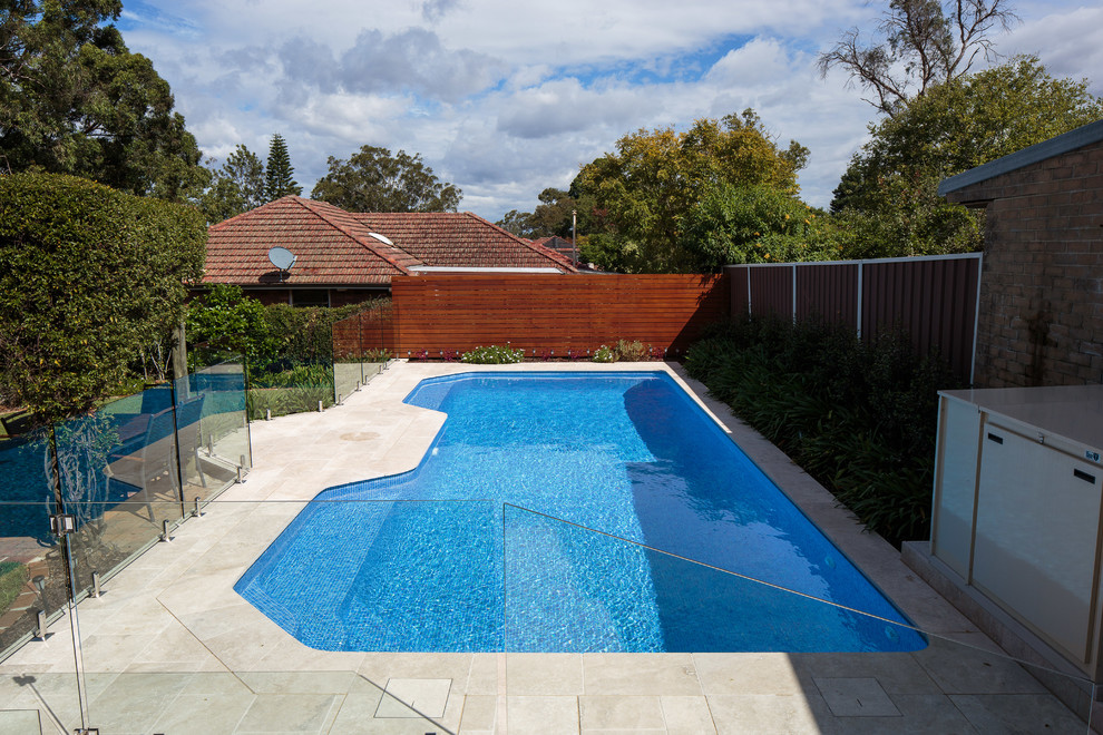 Ejemplo de piscina minimalista de tamaño medio rectangular en patio trasero con adoquines de piedra natural