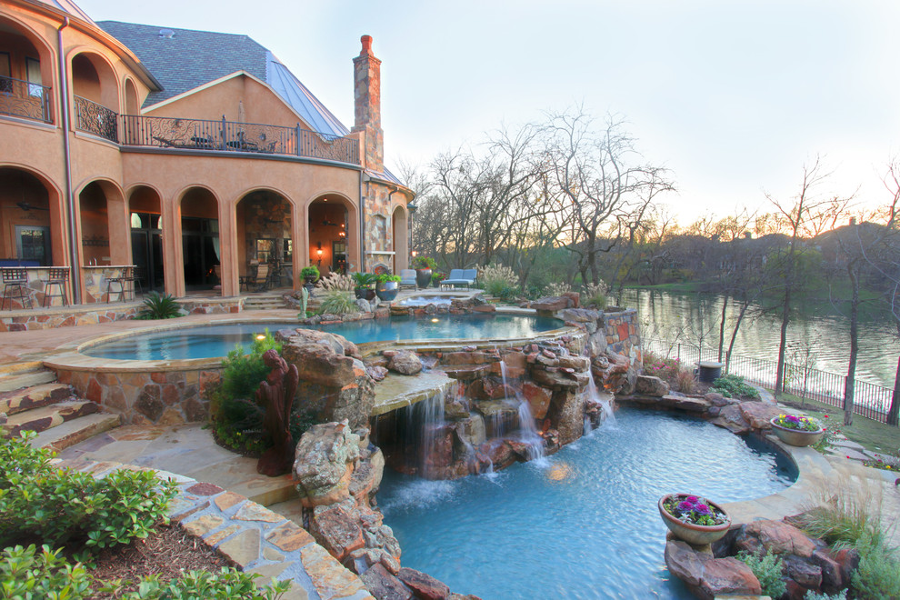 Idee per un'ampia piscina chic personalizzata dietro casa con pavimentazioni in pietra naturale