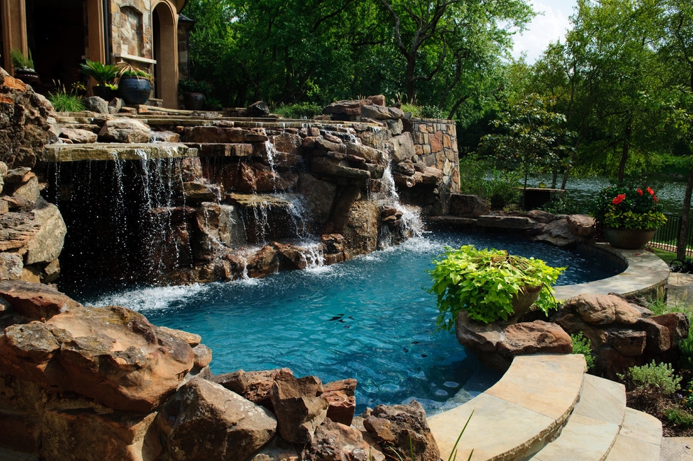 Esempio di un'ampia piscina classica personalizzata dietro casa con pavimentazioni in pietra naturale