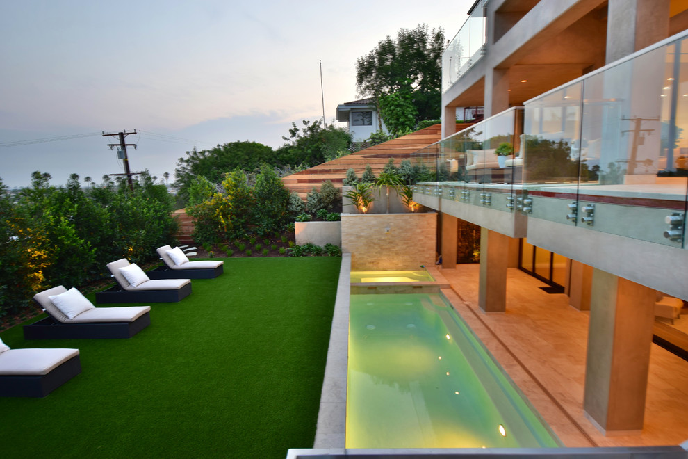 Immagine di una piscina monocorsia minimalista rettangolare di medie dimensioni e dietro casa con una vasca idromassaggio e pavimentazioni in pietra naturale
