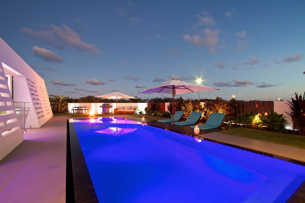 Foto de piscina infinita minimalista de tamaño medio rectangular en patio delantero con suelo de baldosas