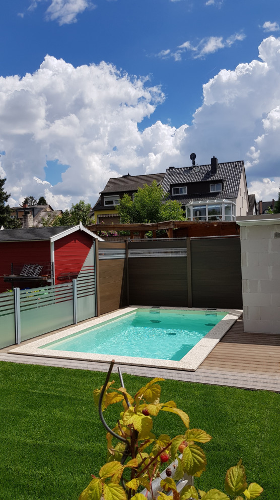 Small mediterranean side rectangular swimming pool in Frankfurt with natural stone paving.