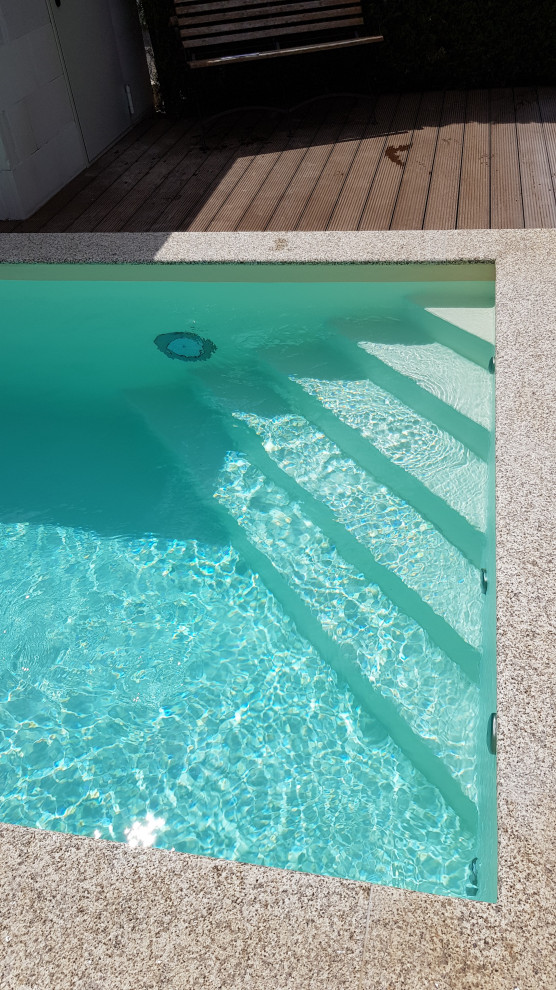 Modelo de piscina mediterránea pequeña rectangular en patio lateral con adoquines de piedra natural