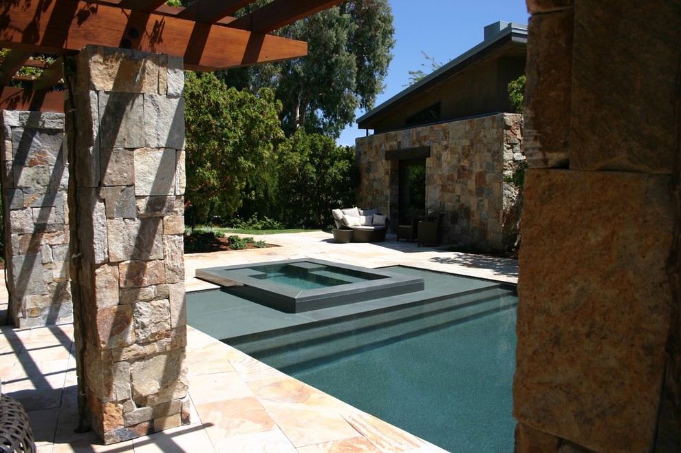 Idee per una grande piscina a sfioro infinito minimal rettangolare dietro casa con una vasca idromassaggio e pavimentazioni in pietra naturale
