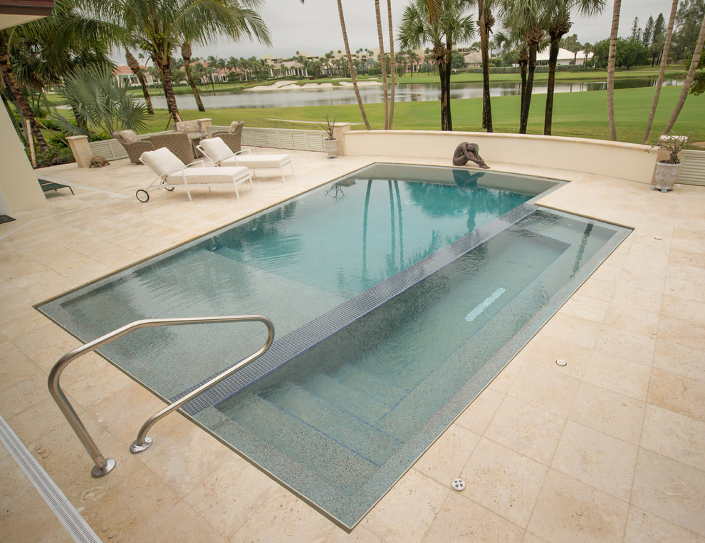 Ispirazione per una piscina a sfioro infinito moderna personalizzata di medie dimensioni e dietro casa con pavimentazioni in pietra naturale