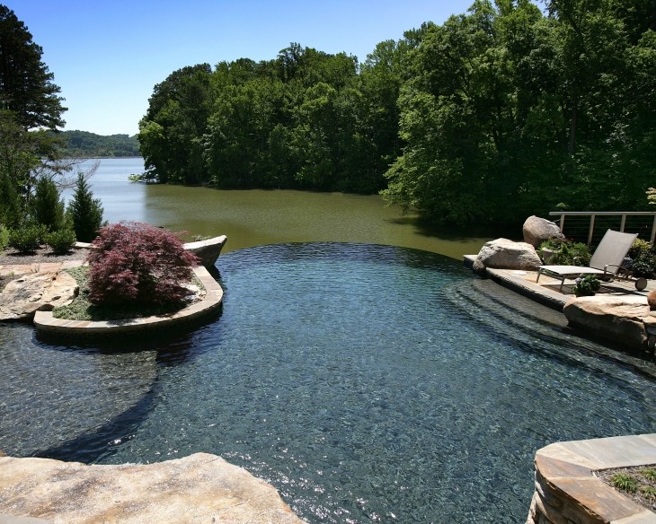 Foto de piscinas y jacuzzis infinitos de estilo americano grandes a medida en patio trasero con adoquines de piedra natural