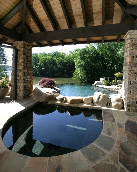 Inspiration pour une grande piscine à débordement et arrière craftsman sur mesure avec un bain bouillonnant et des pavés en pierre naturelle.