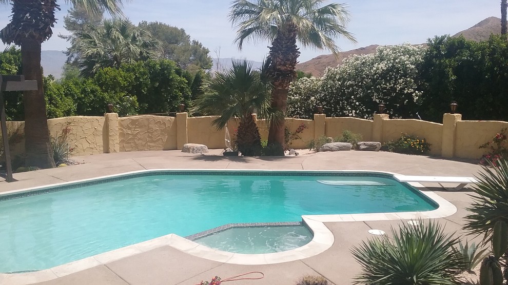 Foto de piscina de estilo americano de tamaño medio a medida en patio trasero con losas de hormigón