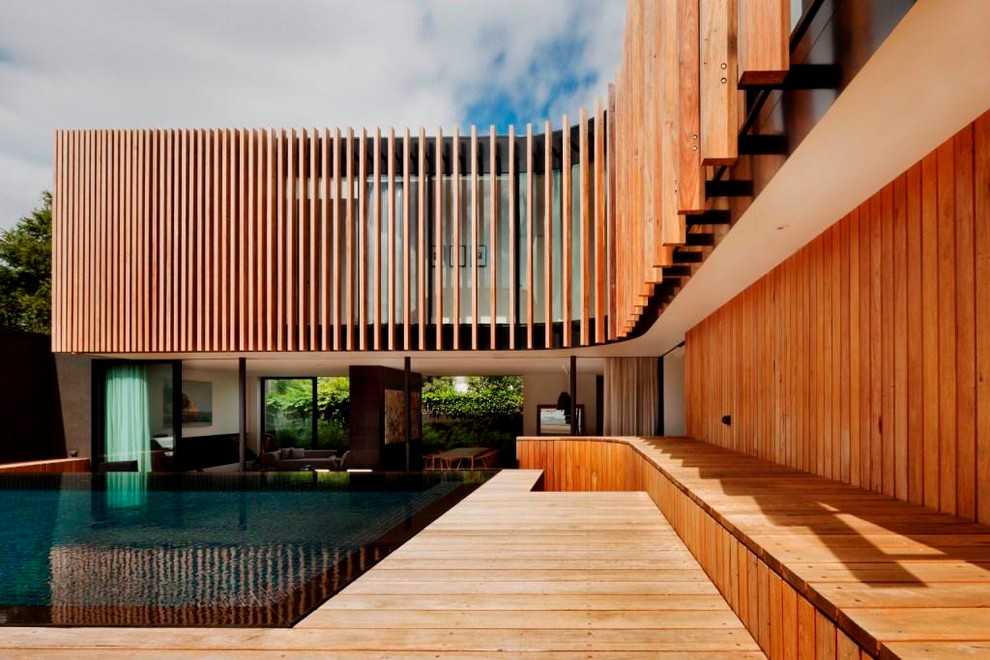 Réalisation d'une piscine arrière design rectangle avec un point d'eau et une terrasse en bois.
