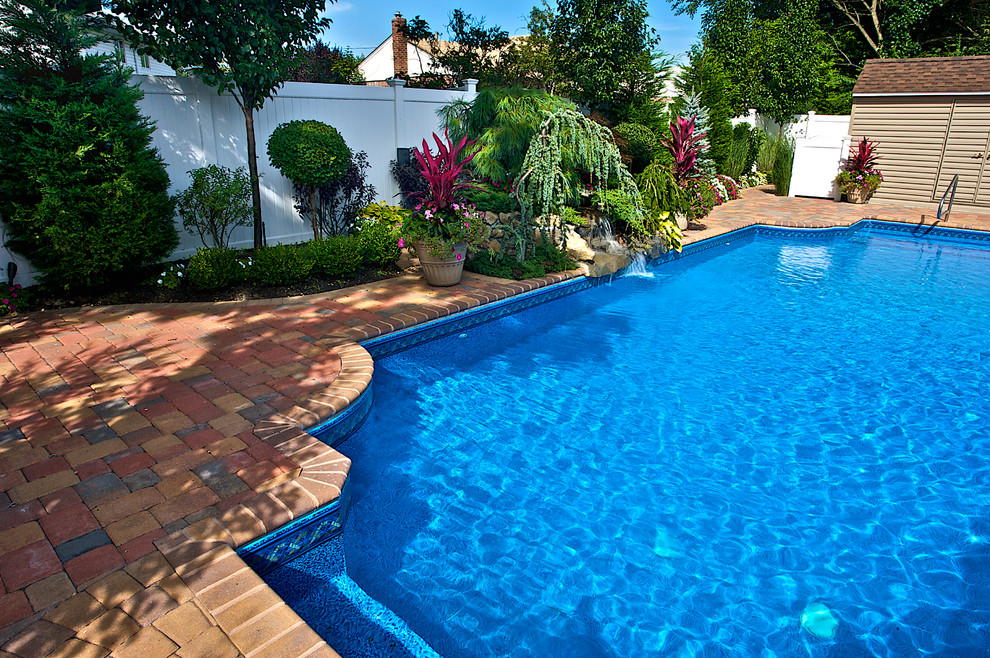 На фото: бассейн среднего размера на заднем дворе в классическом стиле