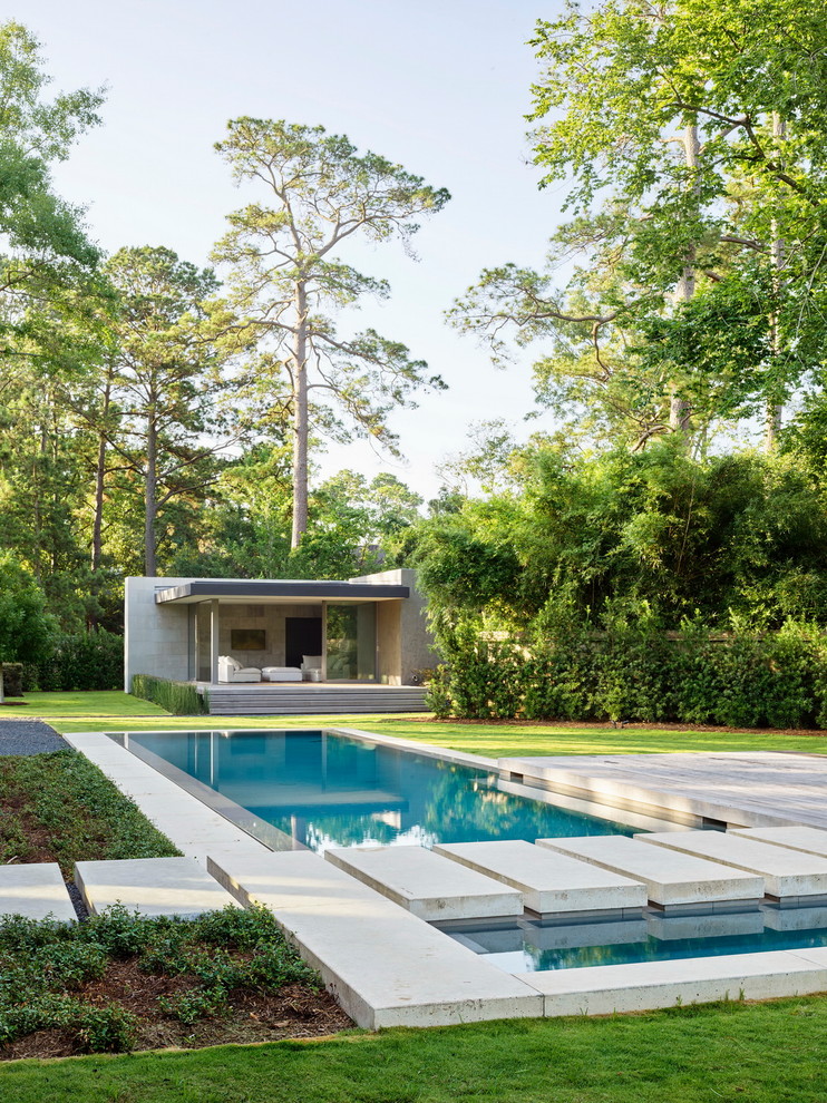 Medium sized modern back rectangular lengths swimming pool in Houston with concrete slabs.