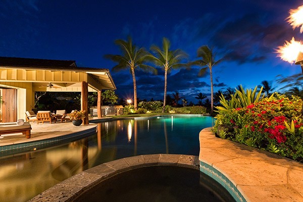 Diseño de piscina infinita tropical grande a medida en patio trasero con adoquines de piedra natural
