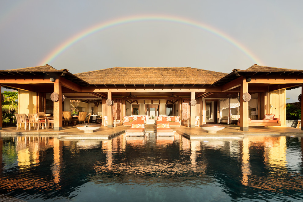 Foto di un'ampia piscina a sfioro infinito tropicale personalizzata dietro casa con una vasca idromassaggio e piastrelle